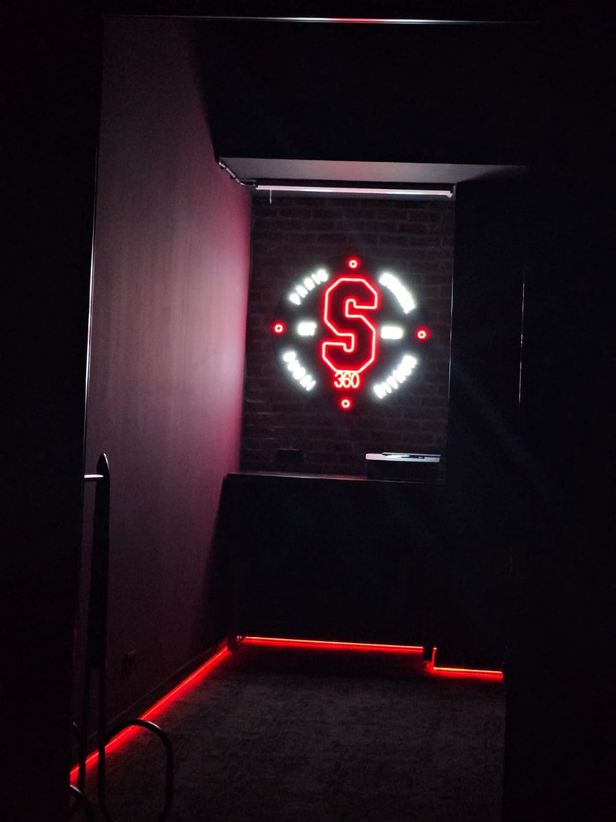 Dark corridor lit by red floor lights, leading to the neon S360 sign