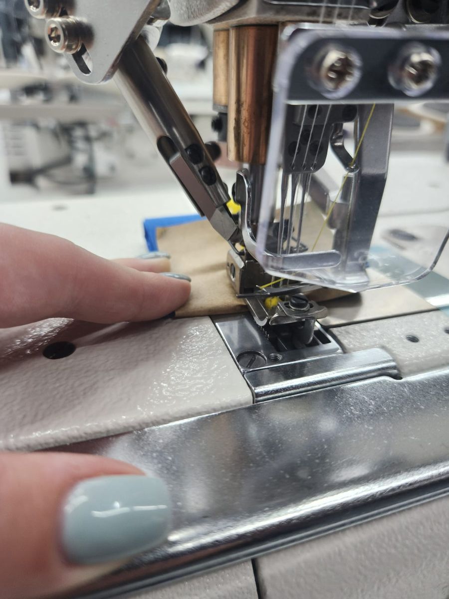 Hands guiding fabric under a sewing machine needle