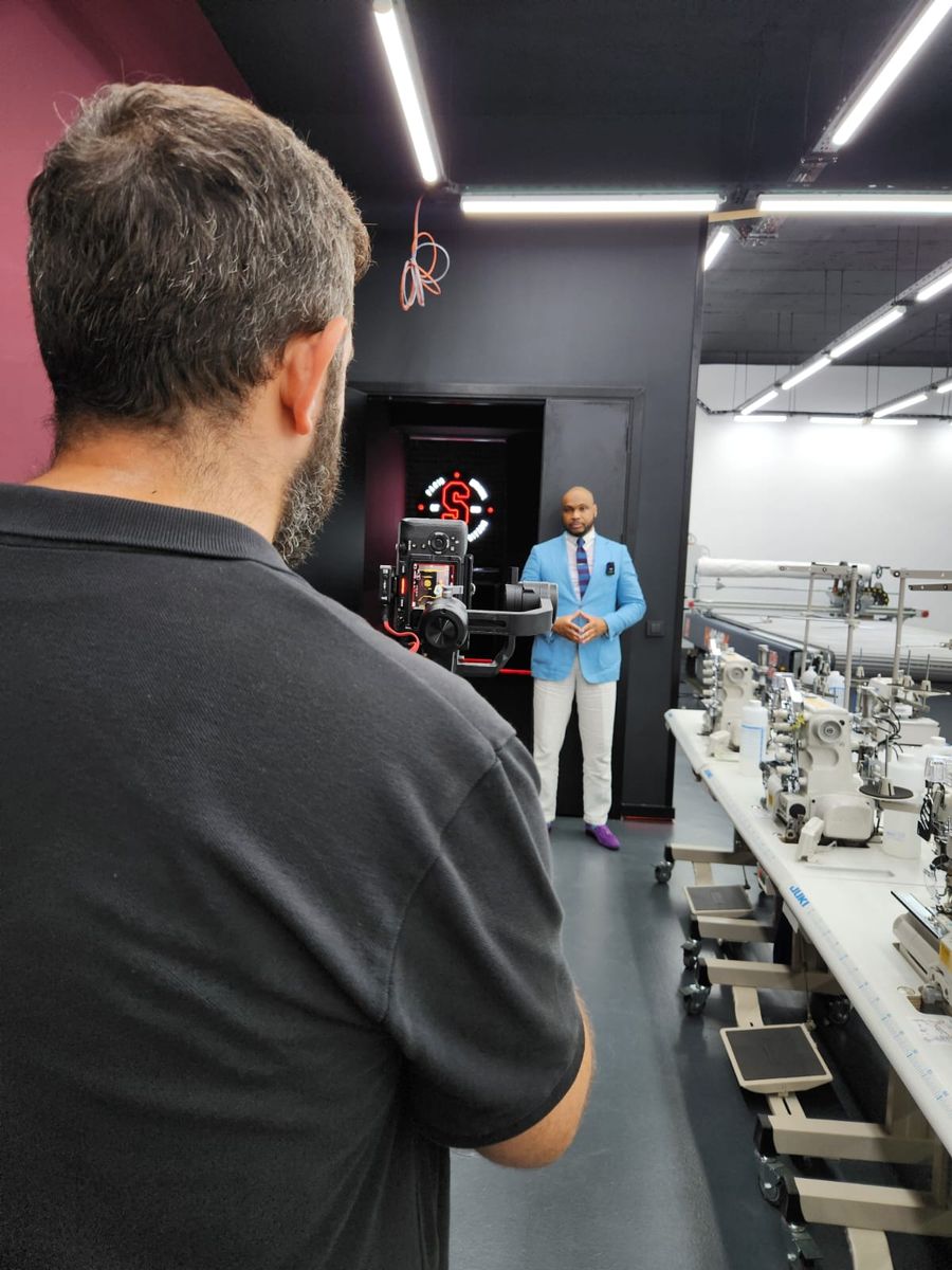 A camera operator filming on the factory floor beside the sewing line