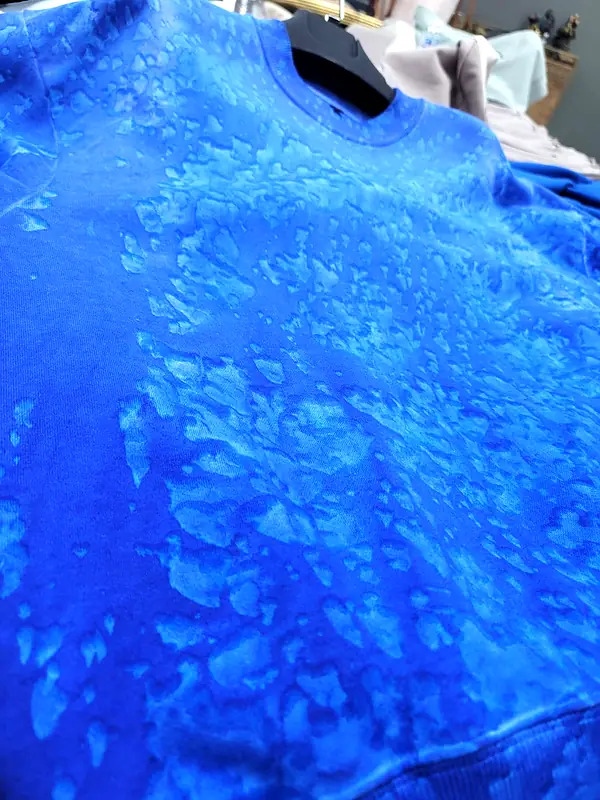 Close-up of a royal blue sweatshirt with a lighter washed pattern
