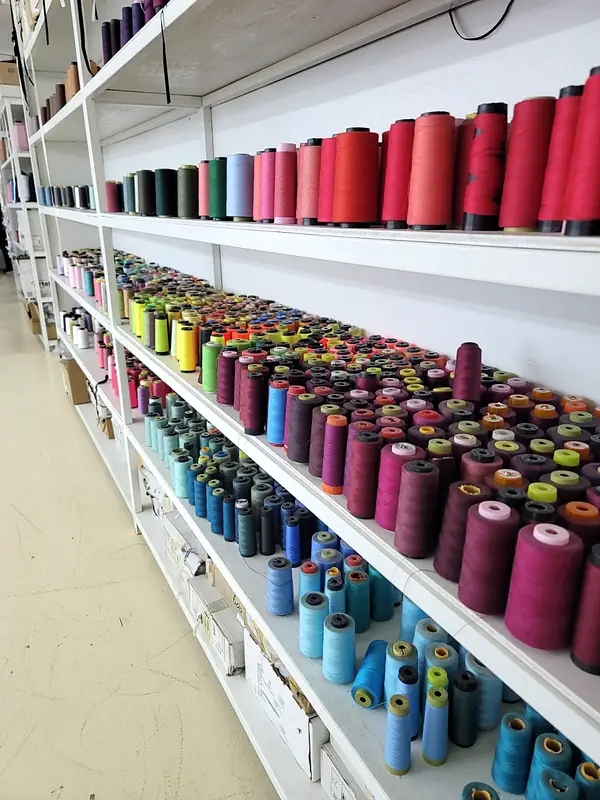 Long white shelves packed with sewing thread cones in every colour