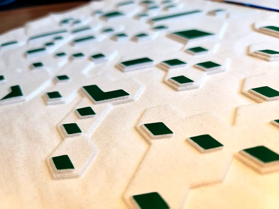 Close-up of a cream fabric with raised green and white silicone shapes
