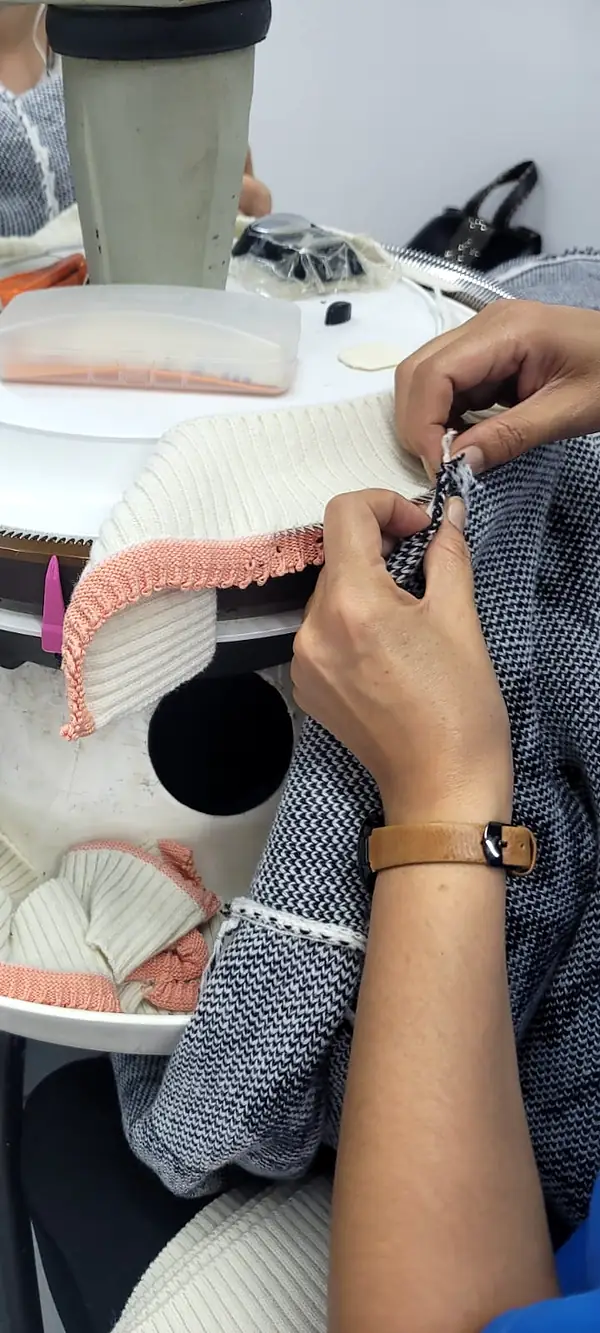Hands feeding a knitted rib trim onto the points of a linking machine