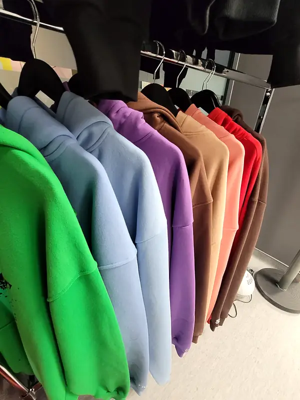 Rail of hoodies in green, sky blue, purple, brown, salmon and red