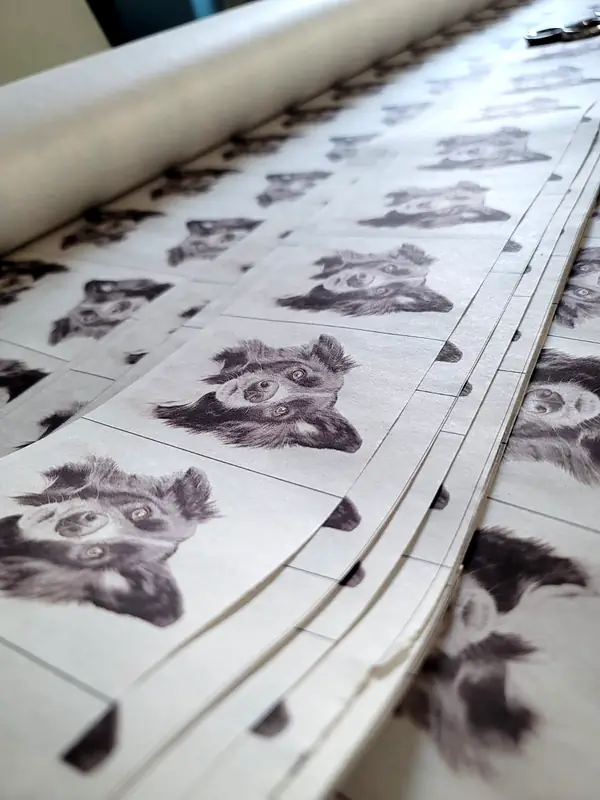 Long sheets of printed heat transfers stacked on a table