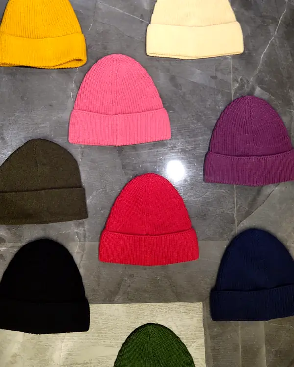 Ribbed beanies laid out in yellow, cream, pink, purple, olive, red, black, navy and green