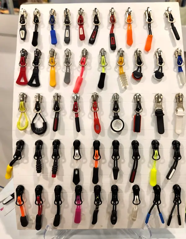Display board of zip sliders with rubber and cord pullers in black, red, orange, yellow and blue