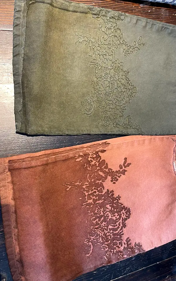 Two garment-dyed twill panels, olive and dusty pink, with a lace pattern etched across them