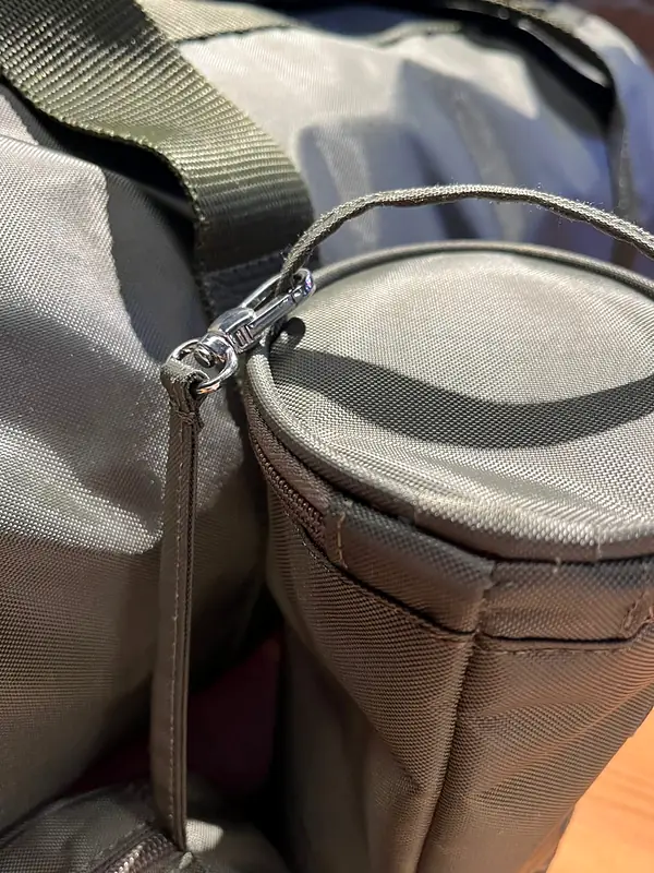 Close-up of a grey nylon bag with a round zip pouch clipped on by a silver swivel hook