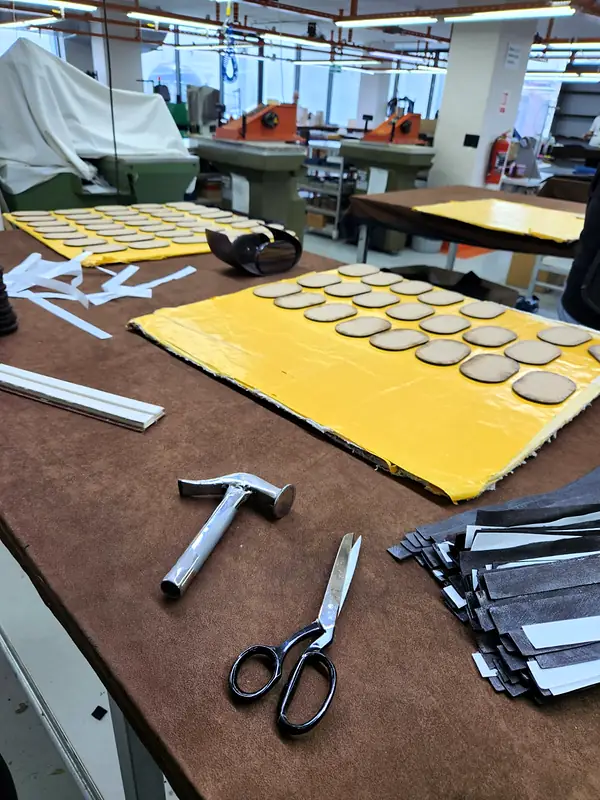 Hammer and scissors next to oval leather pieces glued onto a yellow sheet