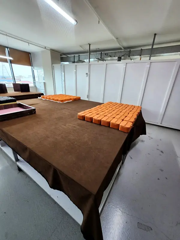 Rows of orange leather cases lined up on a long brown table